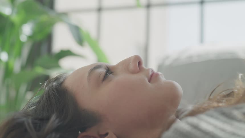 Closeup of a woman laying on her back opening and closing her eyes as if waking up