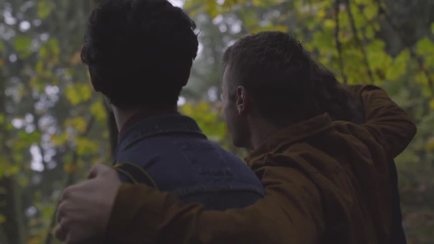 Three men laugh and talk in the woods