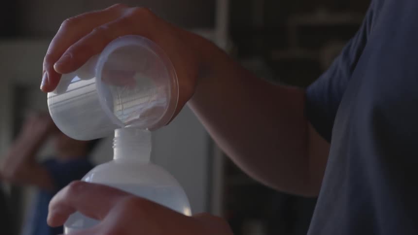 Person pours liquid from beaker into bottle
