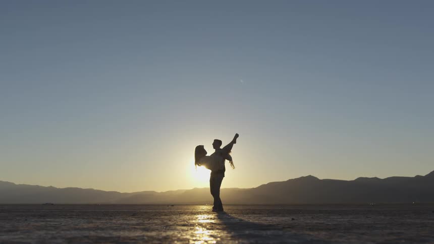A man and woman dance at sunset