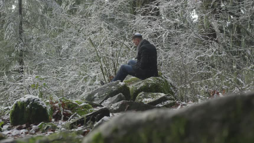 A man sits on a large pile of rocks
