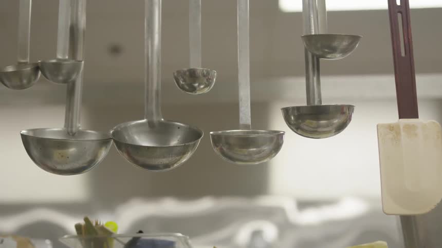 A bunch of ladles that are hanging in a kitchen