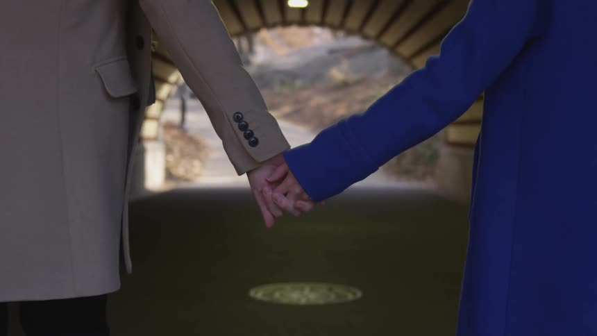 Two people holding hands walking through a small tunnel