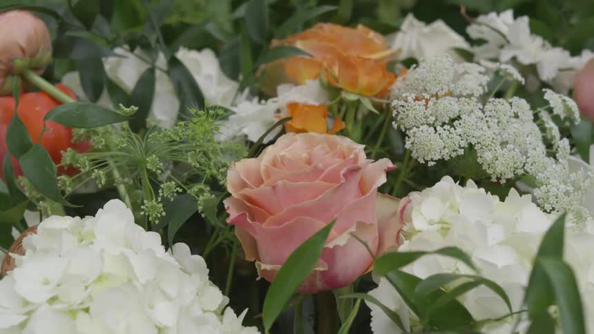 Flower bouquet with white orange and pink flowers is circled around and focused in on