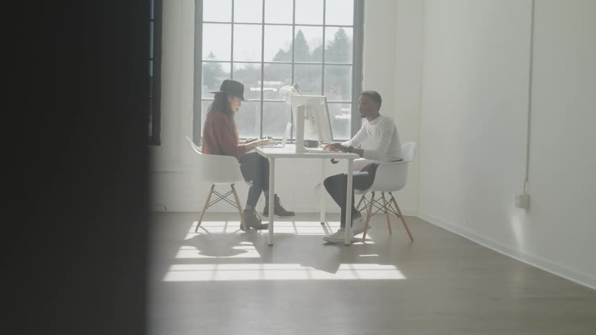 Woman and man are sitting down by a computer