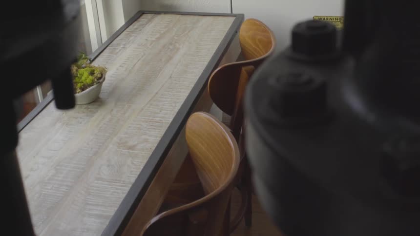 A two seater table and chair against a windowed wall