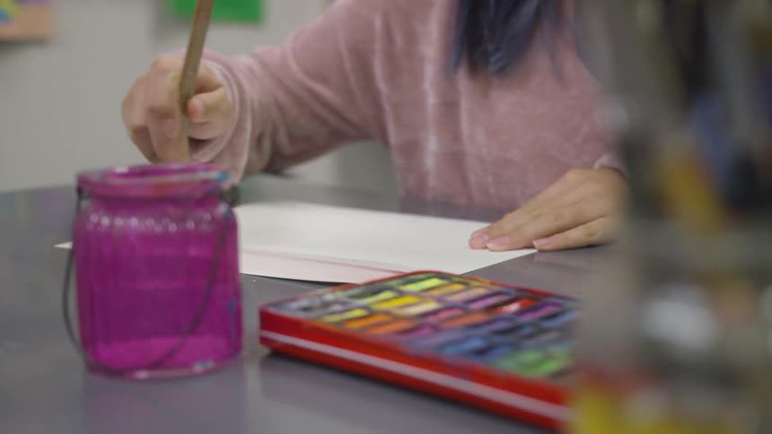 Woman paints paper with brush
