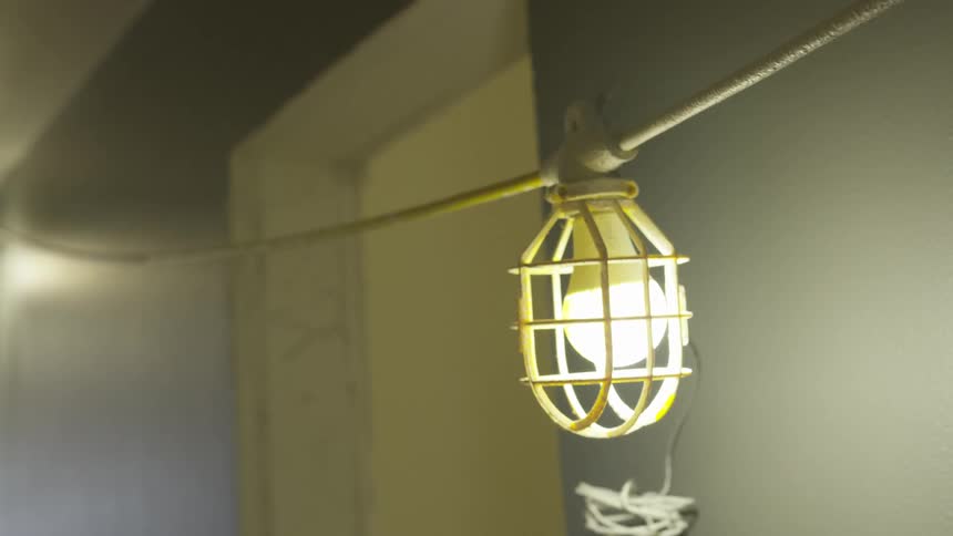 A light hanging from an electrical wire in a room