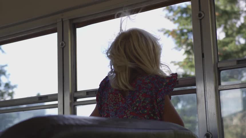 A child's hair blows through the wind from an open window