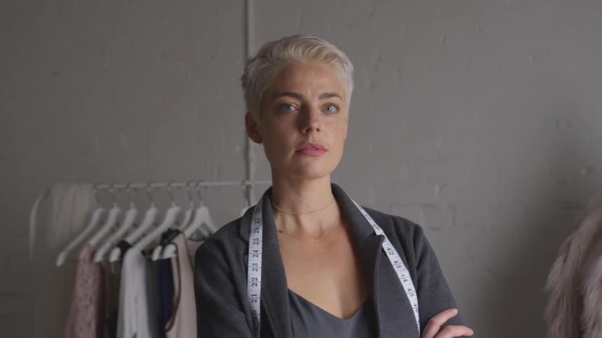Woman with measuring tape around neck turns and looks at camera