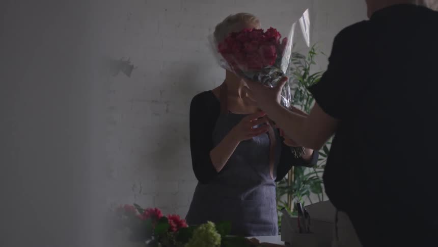 A person that is handing flowers to a man in a store