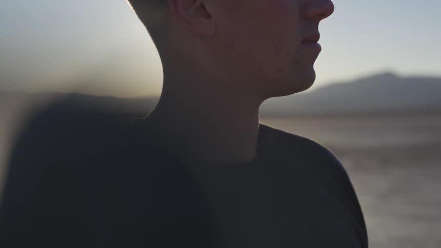 Sun rises behind a man staring in the distance