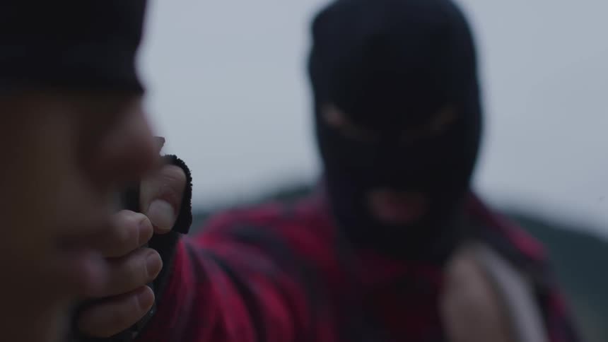 A man holds a gun to a blindfolded woman's face