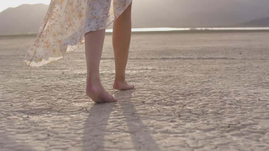 A woman that is walking around on a dry lake bed