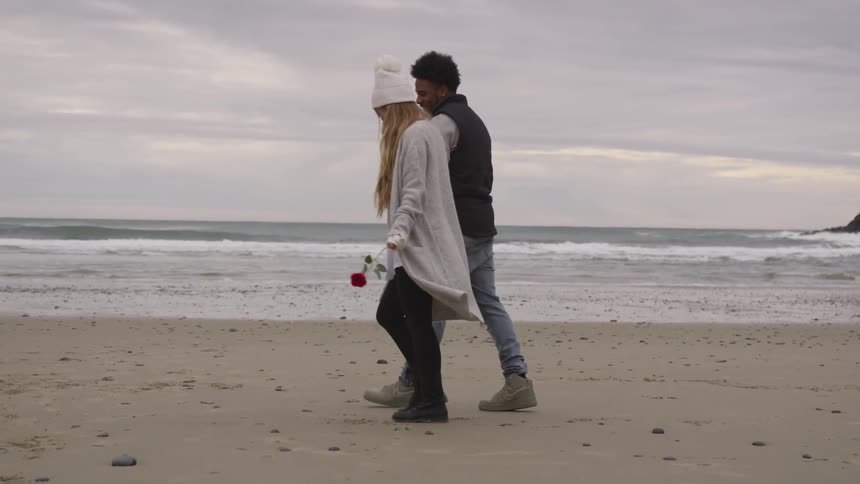 Man and woman walking on a beach while holding hands