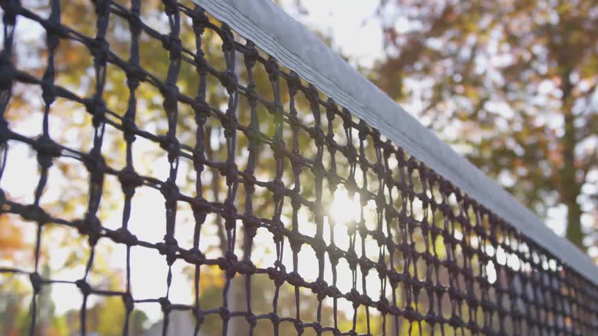 Sunlight shines through a tennis net on a fall day