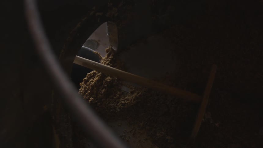 A rake scraping dirt form a machine tank