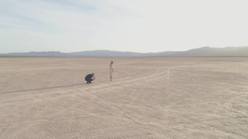 Woman is standing in the desert in white clothes