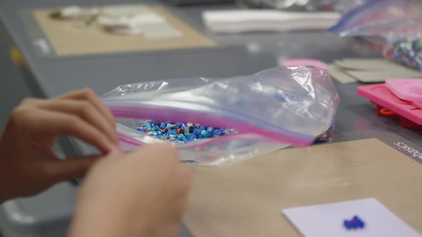 Child takes beads out of bag to make artwork