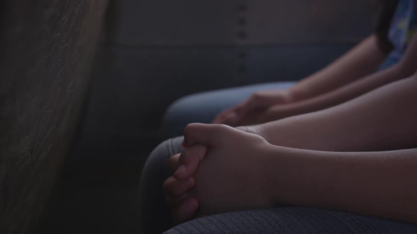 Children sit with their hands clasped