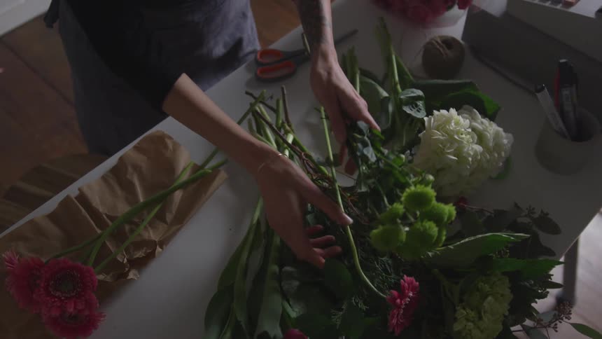 A florist arranges a bouquet of flowers at a desk