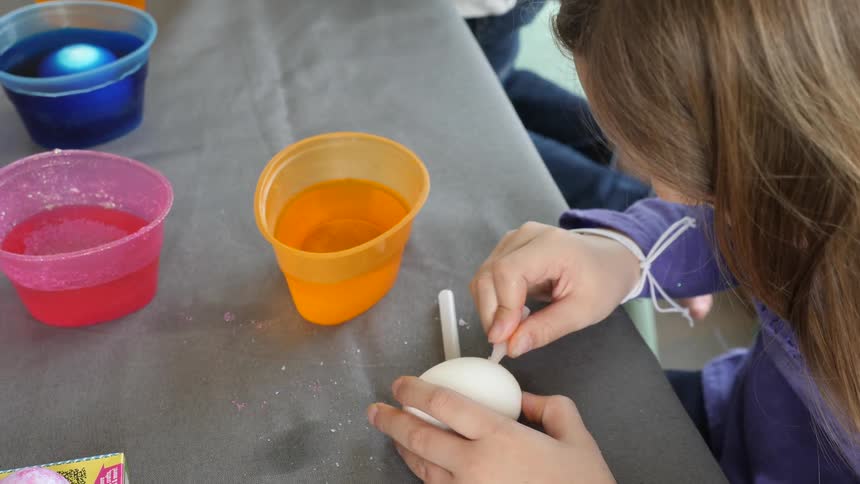 A little girl draws on an egg