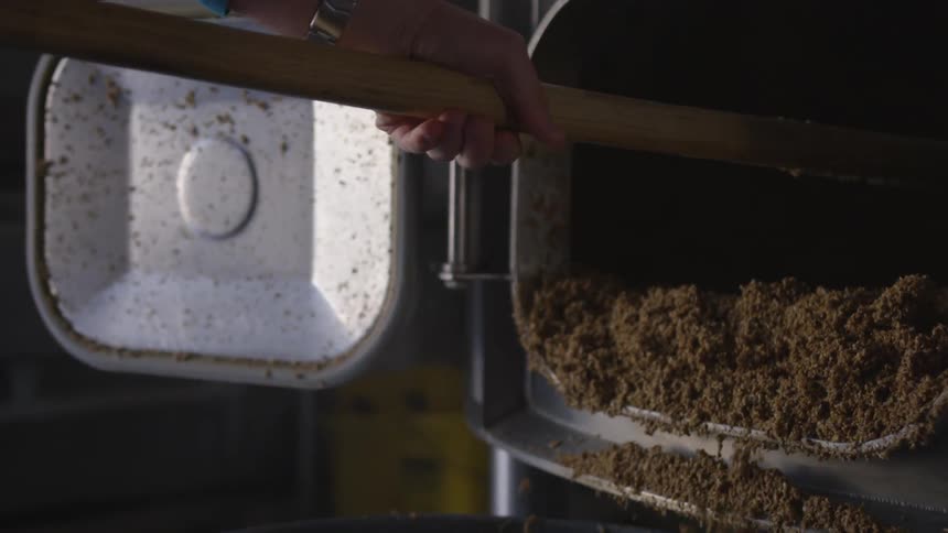 A person is raking dirt out of a compartment