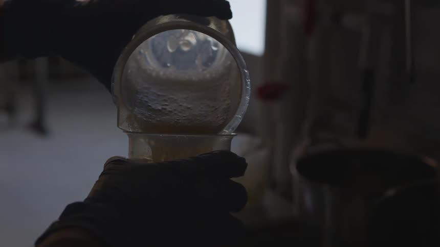 A person is pouring liquids into a cup