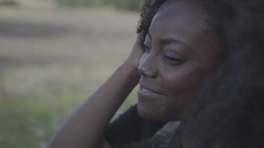 Young black woman nods head in convertible