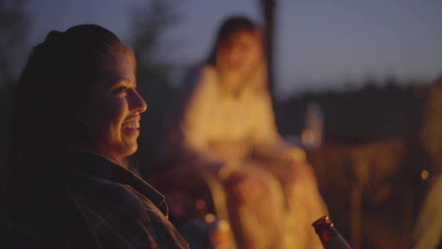 Women laughing together around a fire outside