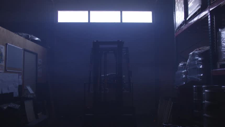 A forklift sits in a dimly lit warehouse