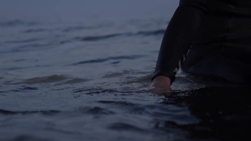 Man sits in water in wetsuit