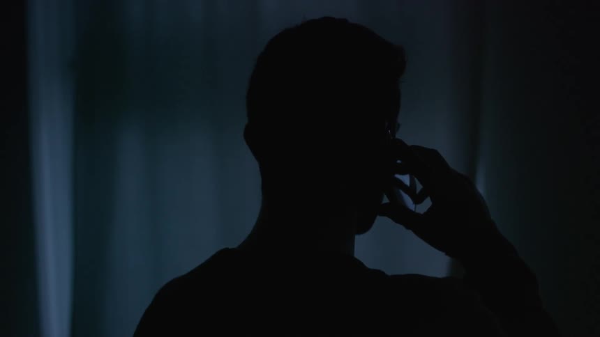 Man talking on a phone in a dark room