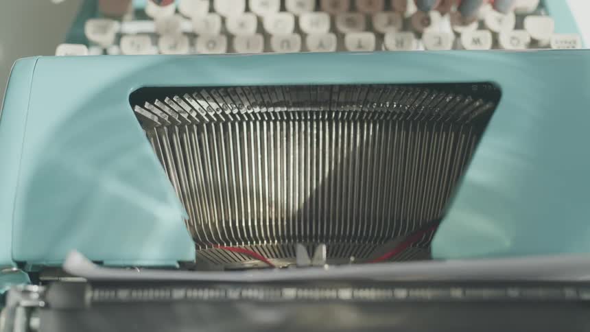 Type bars strike paper as a person types on a typewriter