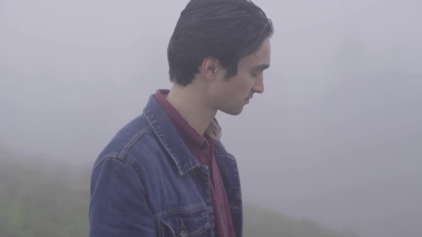 A man standing at the top of a mountain in the fog