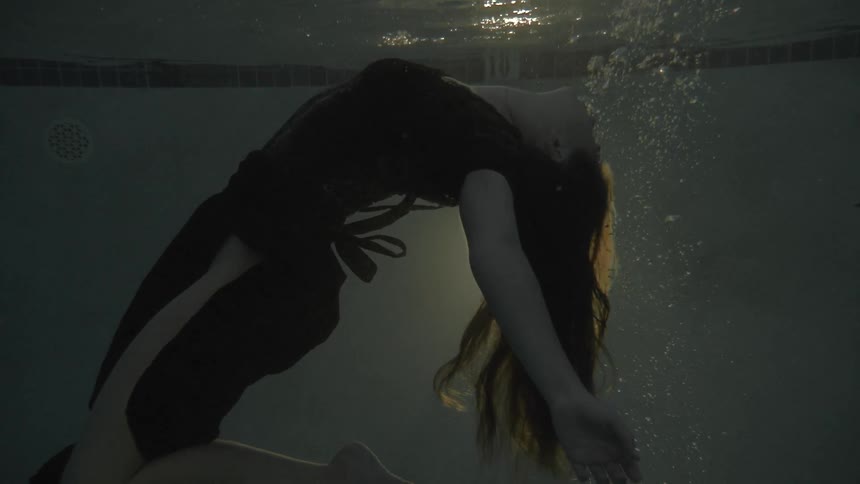 A woman in a dress drowning in a pool