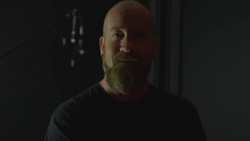 Man with beard raises head to look at camera