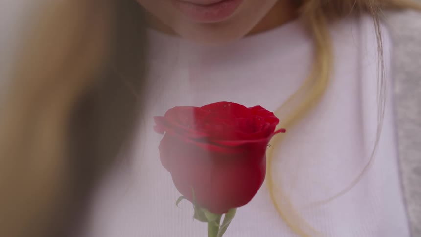 A woman looking down at a rose