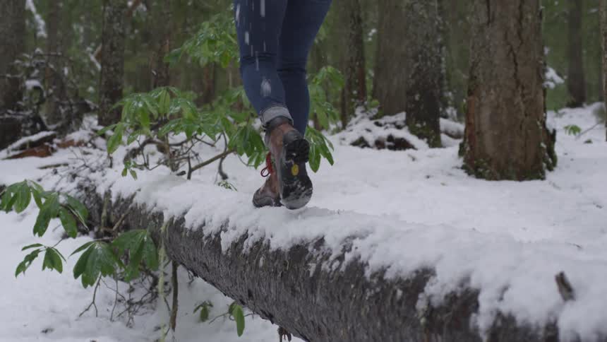 Person balances walking across a log covered in snow