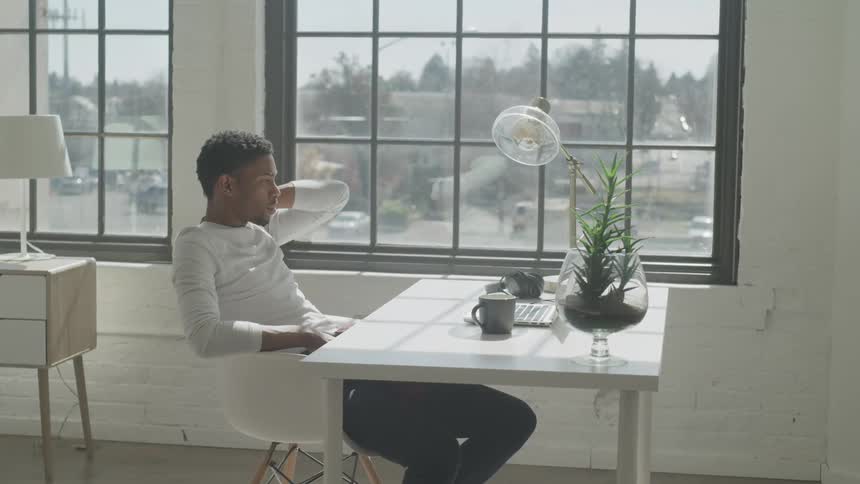 Man sitting in a bright room looking at a laptop