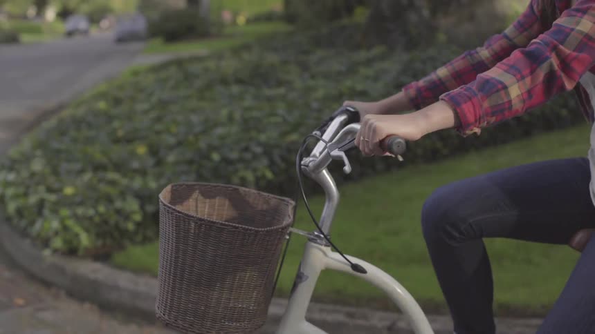 A woman rides a bike with a wicker basket on the front