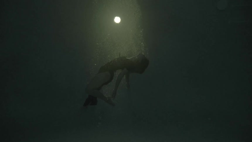 A clothed woman sinks in dark water