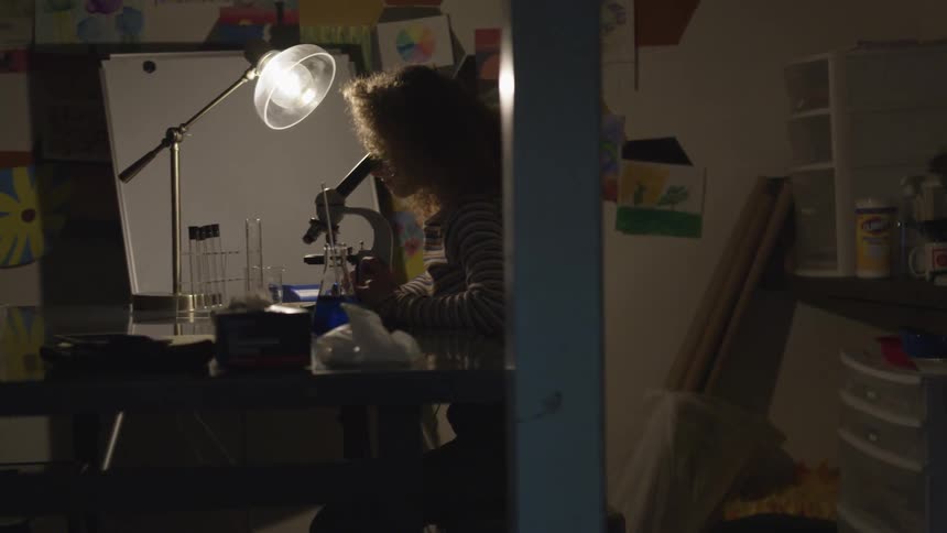 Woman looks through a microscope in a lab