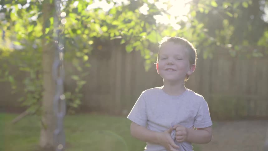 A young child laughs in the yard