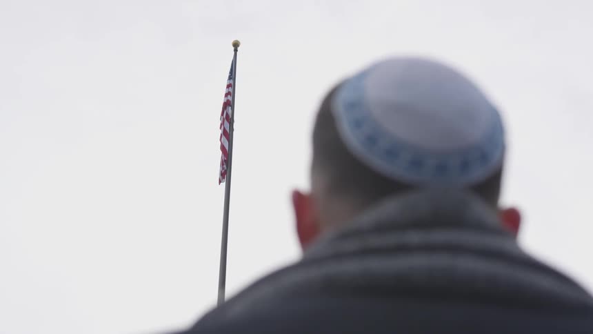 A man wearing a maraca looks up at an american flag