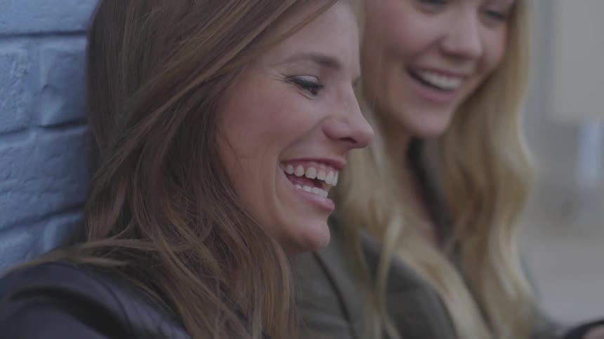 Two women laughing and using their phones