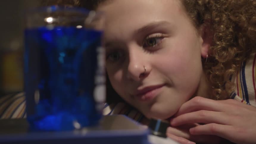 Girl staring at a blue liquid beaker vortex