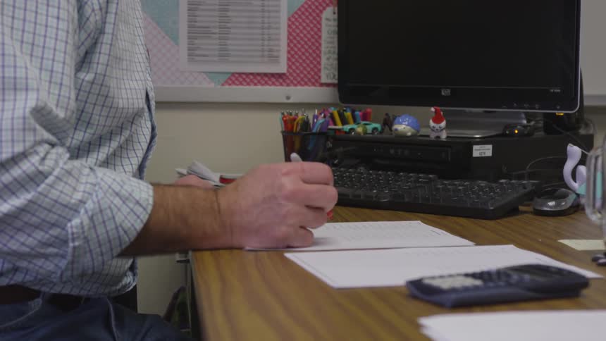 Teacher grades paper while holding red pen