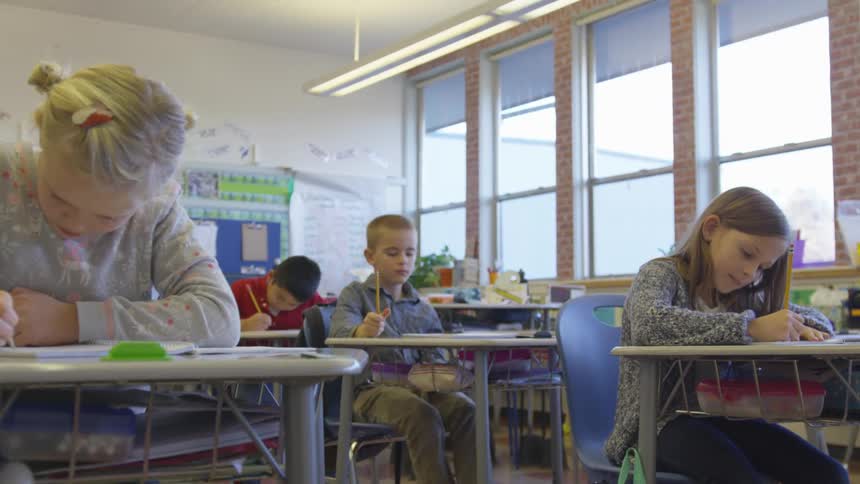 A classroom of children writing at their desks