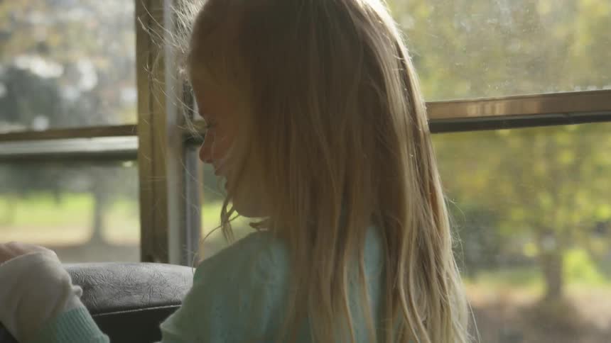 A little girl smiles as she rides a bus
